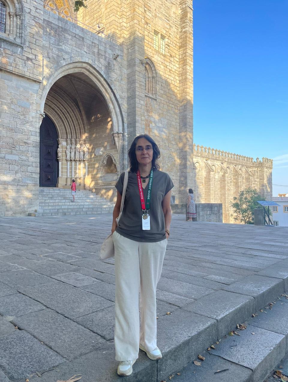 Cidália Soares, guia-intérprete certificada, em frente a um monumento histórico em Évora, Portugal.