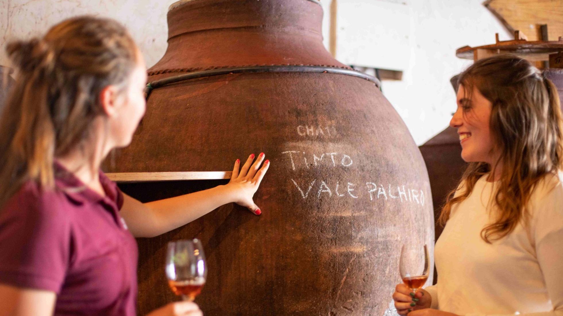 Two people tasting wine directly from a traditional talha in Vila de Frades, Alentejo, Portugal